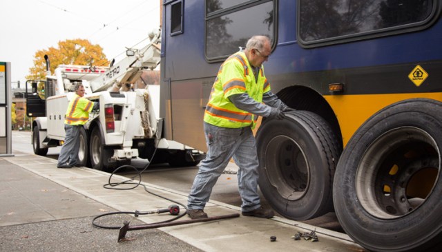 Atlantic Base mechanic Dave Bankson, left, uses the wrecker to lift a disabled bus while Central Base mechanic Walter Olson removes a damaged tire.